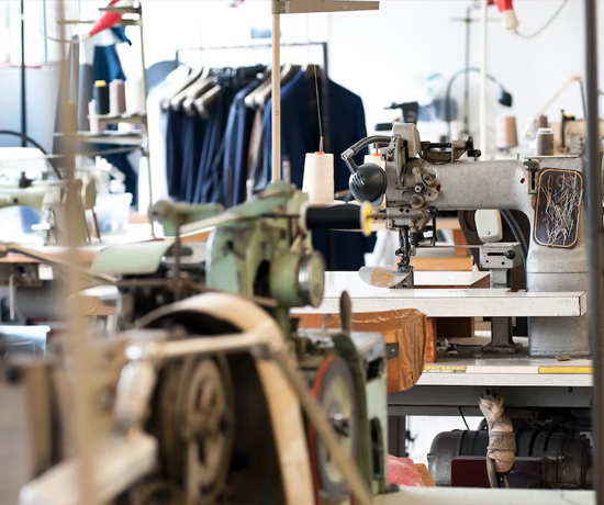 A vibrant sewing workshop filled with vintage sewing machines, spools of thread, and racks of clothing ready for tailoring.